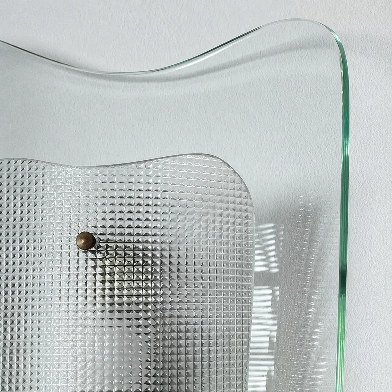 Close view of clear glass wall sconce and textured inner shade