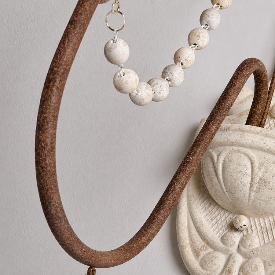 Close view of the curved iron arm and draped wood beads